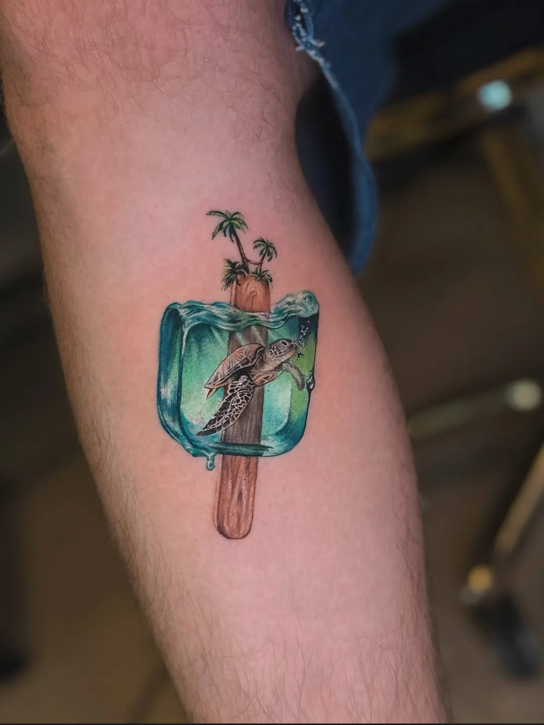 Tatuaj color pe gambă cu o înghețată cu broască țestoasă și palmieri