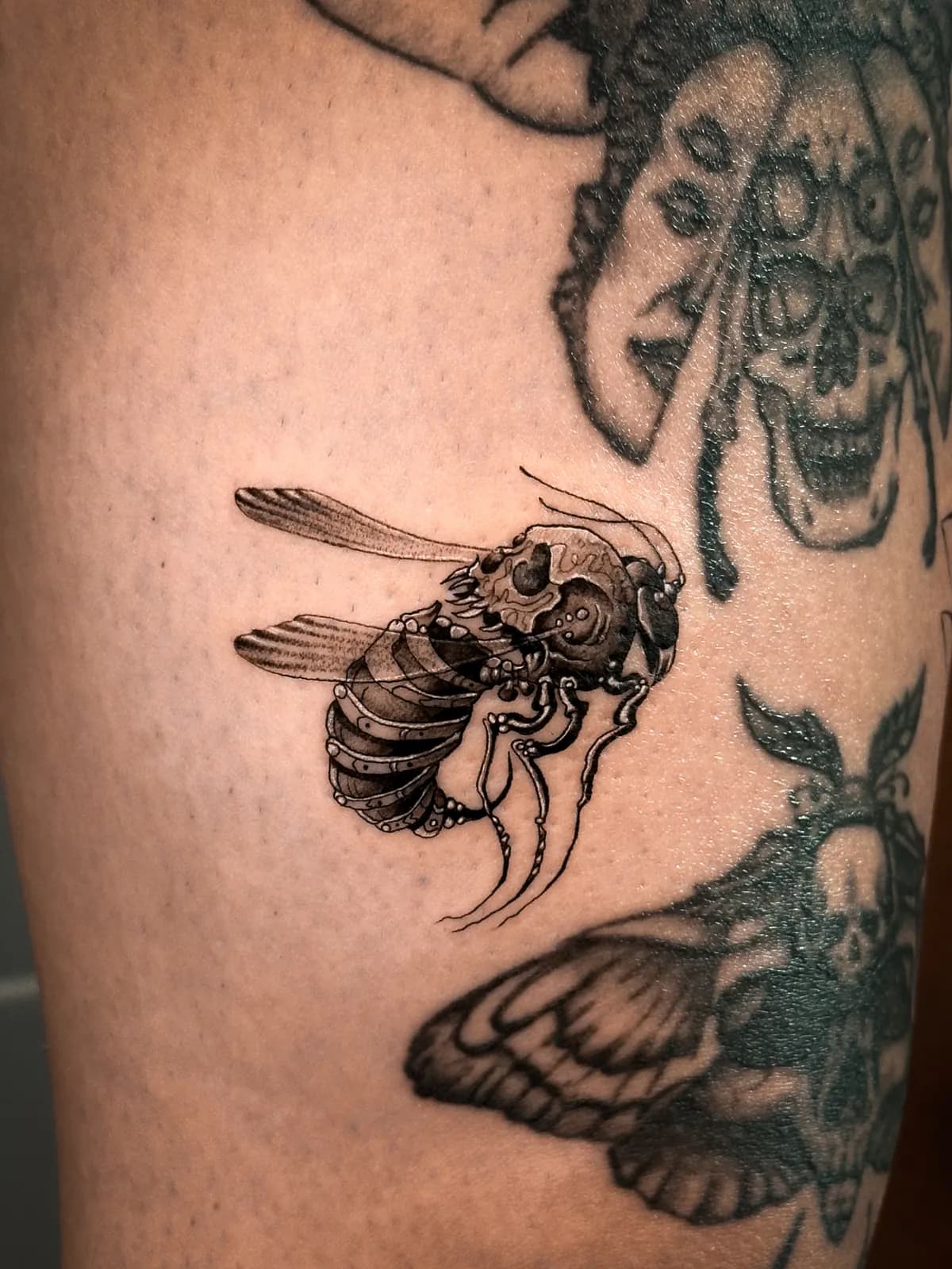 Tatuaj blackwork pe braț cu o insectă cu cap de craniu