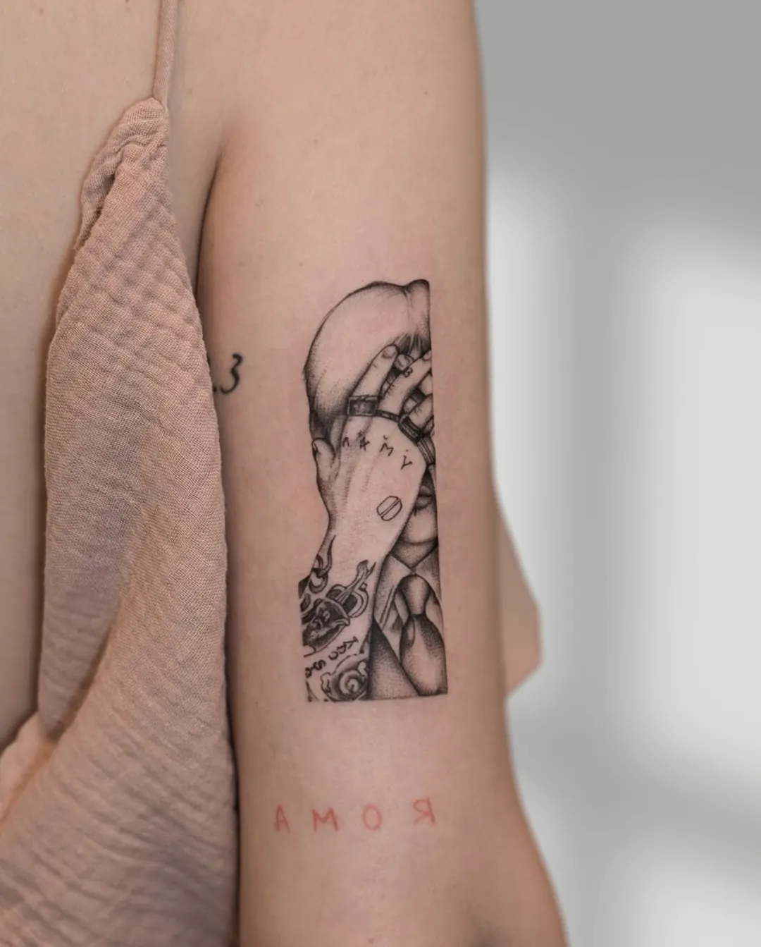 Tatuaj fine line pe antebraț cu mâini acoperind fața și o pastilă