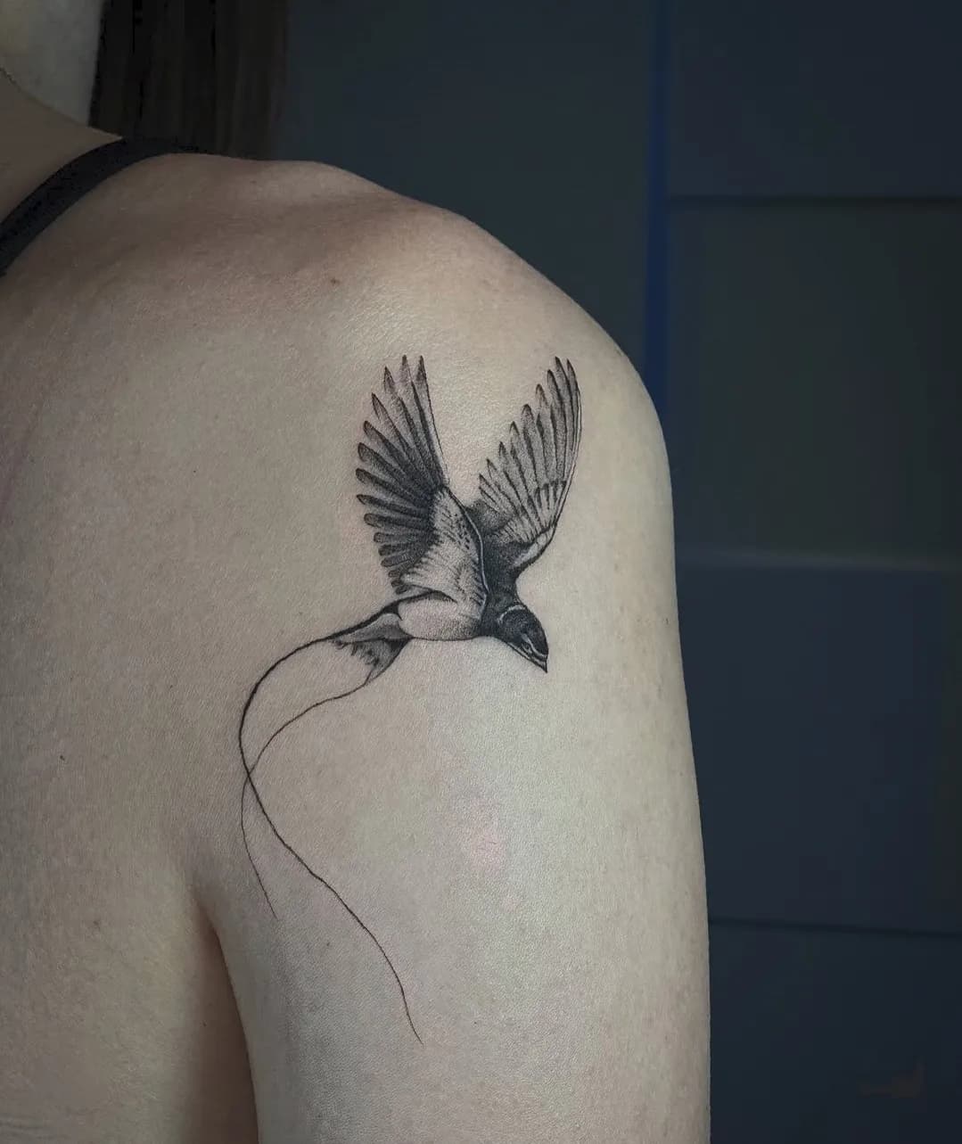 Tatuaj fine line pe umăr cu o rândunică în zbor